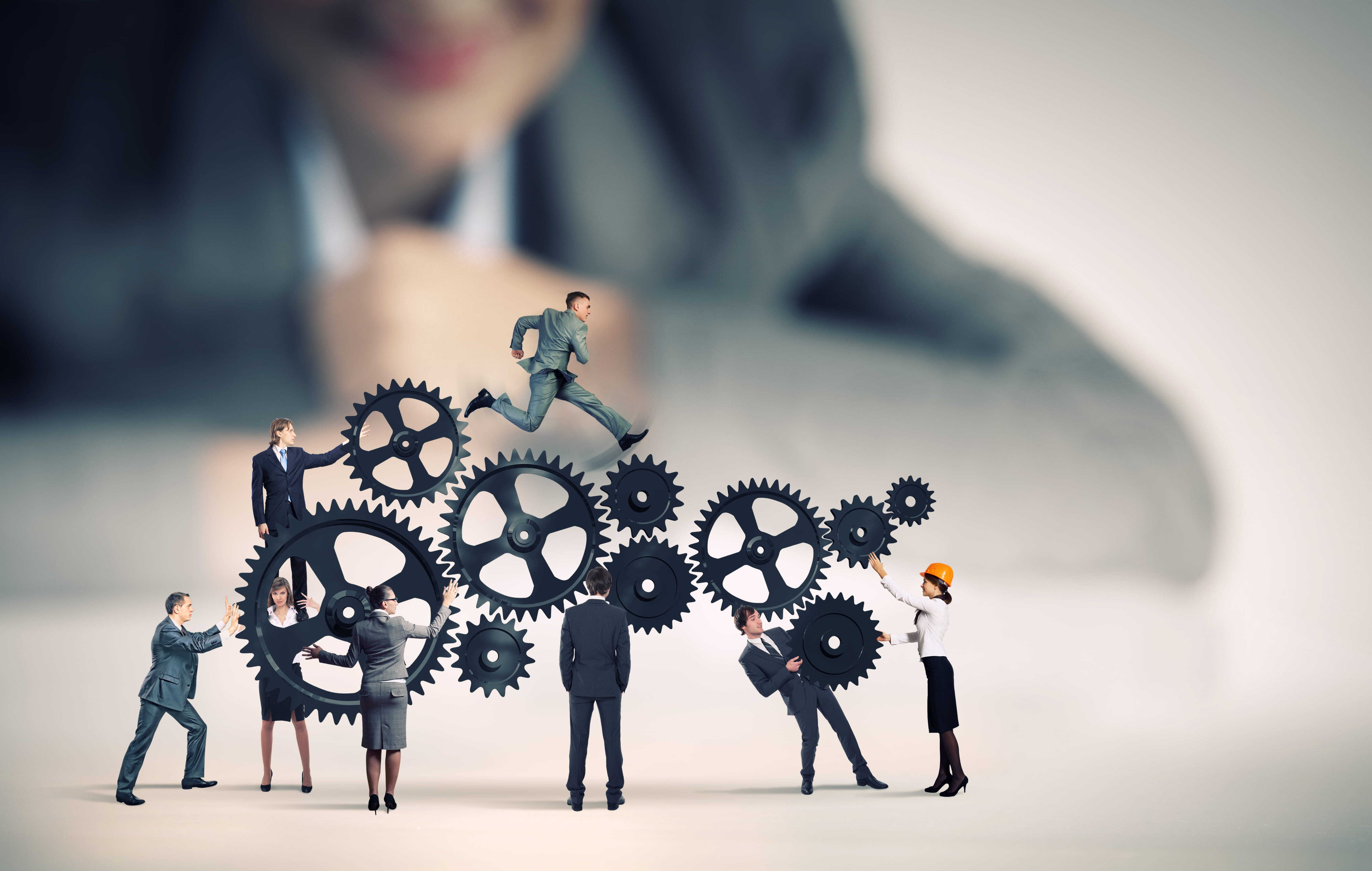 Business team working together around interlocking gears to represent workflow employee efficiency and collaboration.